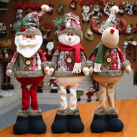 Three Christmas-themed figurines on a wooden surface with a festive background.
